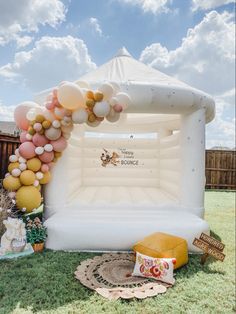 an inflatable arch with balloons on the grass and other decorations around it for a birthday party