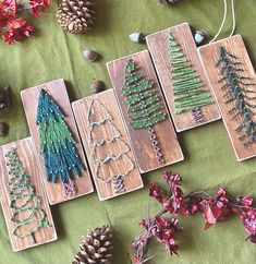 wooden christmas tree ornaments are displayed on a green tablecloth with flowers and pine cones