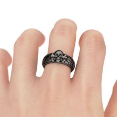 Inspired from Halloween, crafted in black tone sterling silver, this cool skull ring features its skull with bones on the cut-out shank.You can wear the ring separately or stack them together and it will show a unique look on your finger.If you are looking for unique skull jewelry, then take this masterpiece. It won't disappoint you!Carat Weight: 0.057 ctStone Size: 1.5 mmStone Type: Jeulia® StoneNumber of Stones: 2 Stone Color: Fancy BlackStone Shape: RoundWeight: 5.42 gWidth: 8.6 mmHeight: 5.5 mmThickness: 4.9 mmMaterial: 925 SilverPlating Color: Black Infinity Rings Engagement, Skull Wedding Ring, Skull Engagement Ring, Diamond Skull, Sterling Silver Skull Rings, Skull Rings, Skull Wedding, Silver Skull Ring, Black Engagement Ring