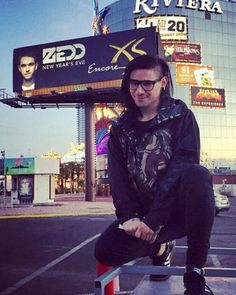 a man sitting on top of a metal bench in front of a large sign and building