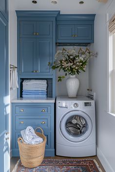 a washer and dryer in a small room with blue cabinetry, drawers, and rug