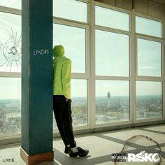 a person in a yellow jacket leaning against a wall with graffiti on it and looking out the window