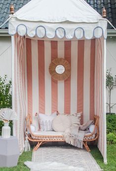 a white and pink striped tent sitting on top of a lush green field