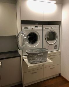 a washer and dryer in a laundry room with cabinets on either side, next to each other