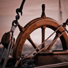 an old wooden steering wheel on the deck of a boat