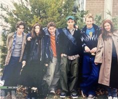 a group of young people standing next to each other in front of a tree and building