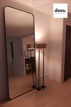 a large mirror sitting on top of a wooden floor next to a lamp and table