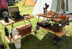 two tables with pots, pans and utensils on them in the grass