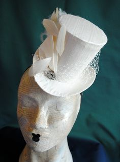 This simple and elegant bridal mini top hat is covered with beautiful ivory silk shantung. It is embellished with ivory veil, a luxurious spray of curled ostrich plums and a sparkling flower shaped rhinestone button. Also available in white and black here : https://www.etsy.com/shop/BizarreNoir?ref=seller-platform-mcnav&section_id=14329940 If you're interested in another color, please, send me a message to talk about your options. This mini top hat is fully lined with satin and attaches to t Fitted Cream Costume Hats And Headpieces For Ceremony, White Fitted Top Hat With High Crown, Elegant Top Hat With Short Brim For Costume, Elegant Short Brim Top Hat For Costume, Elegant Fitted Costume Hat With Tall Crown, Elegant Costume Top Hat With Short Brim, White Fitted Mini Hats For Vintage Events, Elegant Tall Crown Adjustable Hat, Whimsical Fitted Top Hat With Short Brim