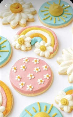 decorated cookies with flowers and rainbows are on a white table top next to each other