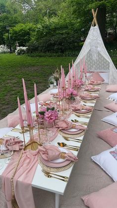 the table is set with pink napkins and place settings for an outdoor dinner party