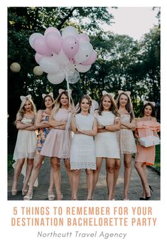 a group of women standing next to each other holding pink and white balloons