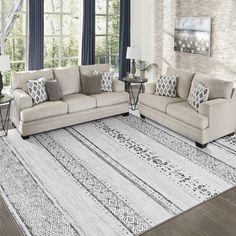 a living room with two couches and a rug in front of a window on the floor