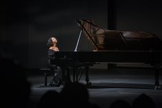 a woman sitting at a piano in the dark