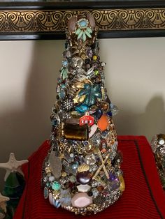 a christmas tree made out of jewelry on a red table cloth next to a mirror