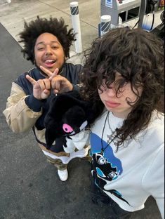 two people standing next to each other on the street with one holding a stuffed animal