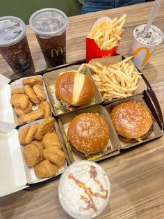 several trays of food including burgers, fries and sodas on a table