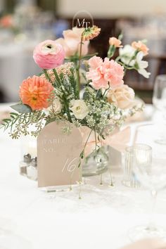 an arrangement of flowers in vases on top of a white table cloth covered table