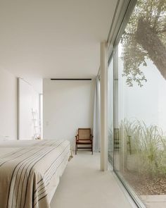 a bedroom with a large bed next to a glass wall that looks out onto the outdoors