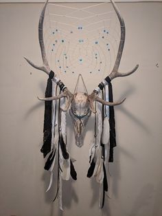 an animal's head is mounted on the wall with feathers and bead work