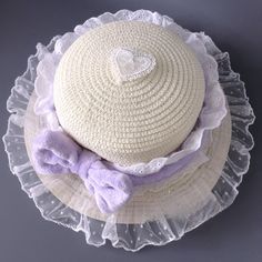 This elegant straw hat features a plush bow embellishment, intricately adorned with delicate lace trimmings. The hat's crown is further enhanced with a heart-shaped lace applique, adding a touch of charm and sophistication.  Please note: The price includes one hat only. Cute White Hats With Bow, Cute White Hat With Bow, Summer Wide Brim Hat With Ruffles, Summer Brimmed Hat With Ruffles, Purple Crochet Summer Hat, Summer Bucket Hat With Ruffles, Summer Ruffled Bucket Hat, Purple Mini Hat For Summer Beach, Beach Hat With Ruffles And Curved Brim