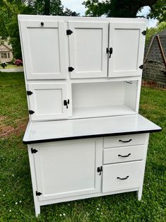 an old dresser is painted white and has black knobs on the doors, drawers, and shelves