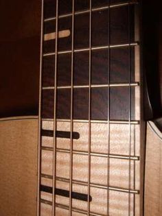 an acoustic guitar is sitting on the floor in front of a wall with wood paneling