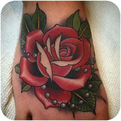 a foot with a rose tattoo on it and pearls around the toe area, as well as some leaves