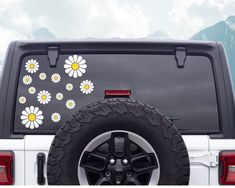 the back end of a white truck with flowers painted on it's rear tire