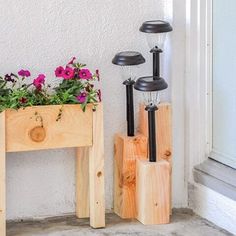 two wooden planters with flowers in them sitting next to each other on the side of a building