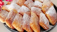 a plate full of powdered sugar pastries on a table