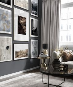 a living room with gray walls and pictures on the wall above the coffee table in front of the couch