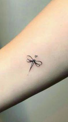 a small dragonfly tattoo on the arm