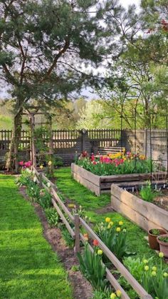 an outdoor garden with lots of flowers and plants in the center, surrounded by wooden fences