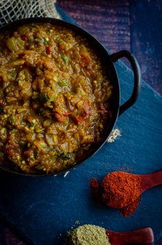 a pan filled with food sitting on top of a blue cloth next to some spices