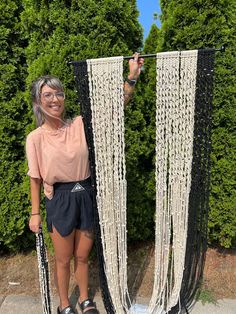 a woman standing next to two black and white macrame chains with her hands in the air