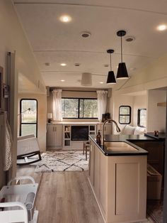 a kitchen and dining area in a mobile home with wood flooring, white walls and ceiling lights