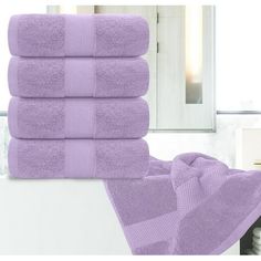 a stack of purple towels sitting on top of a bathroom counter