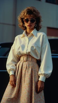 A confident woman in an iconic 80s outfit featuring a white blouse, high-waisted floral skirt, and oversized sunglasses. 1980s American Fashion, 70 80 90 Fashion Outfit, 80 Aesthetic Fashion, 80s Iconic Outfits, 80s Era Fashion, 80s Casual Fashion, 80s Casual Outfit