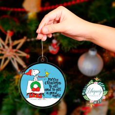 a hand holding a christmas ornament in front of a christmas tree