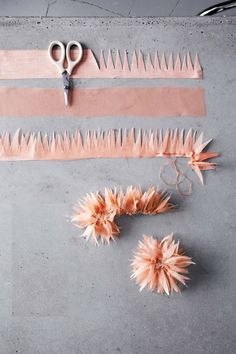 two pairs of scissors and some flowers on a gray surface with pink strips of fabric