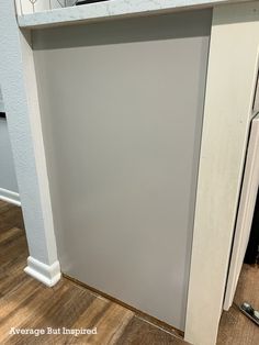 an empty kitchen with white cabinets and wood flooring