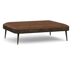 a brown ottoman sitting on top of a wooden table