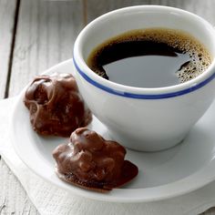 two pieces of chocolate on a plate next to a cup of coffee