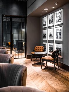 a room with chairs, tables and pictures on the wall in front of glass doors