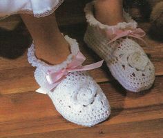 a pair of white crocheted shoes with pink bows