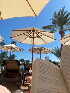 an open book sitting on top of a table next to umbrellas and lawn chairs