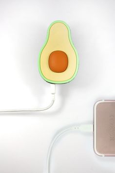 an avocado shaped phone charger is plugged into the wall with a cord