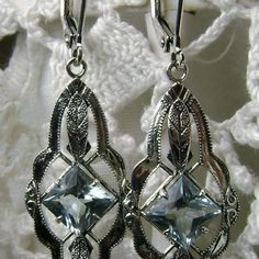 These are Art Deco reproduction estate earrings in sterling silver set with flawless high quality blue topaz gemstones. Each stunning 1.18ct blue topaz is 6mm long/wide (1/4th"). The earrings are 1 3/4th inches long and 14mm (1/2") at its widest point. Notice the beautiful leaf on the bottom and top of the setting. These lovely earrings were fashioned from an antique art deco brooch. Silver Blue Topaz Drop Earrings, Art Deco Gemstone Earrings For Gift, Silver Sterling Silver Art Deco Earrings, Nickel Free Blue Topaz Earrings For Anniversary, Hallmarked Silver Jewelry With Blue Topaz, Ornate Silver Blue Topaz Jewelry, Silver Gemstone Art Deco Earrings, Art Deco Silver Gemstone Earrings, Silver Blue Topaz Earrings Fine Jewelry