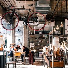 two people are sitting at a table with bicycles hanging from the ceiling